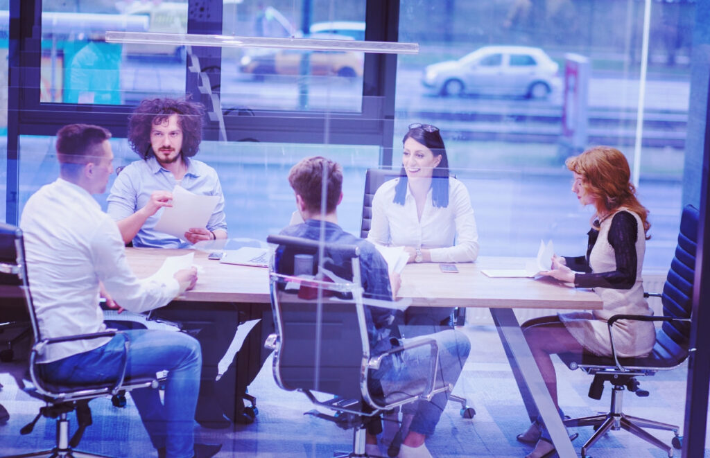 Reunião de trabalho em uma sala corporativa, com colegas discutindo estratégias para lidar com conflitos na equipe.