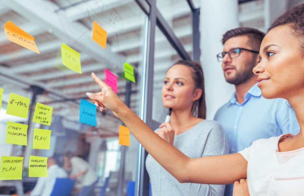 Equipe de trabalho reunida em frente a um painel de post-its